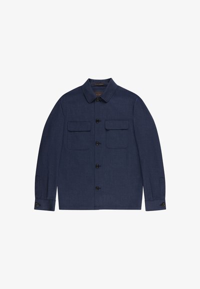 Granatowa kurtka zapinana na guziki z ostrym kołnierzem, dwoma klapkowymi kieszeniami na piersi i mankietami na guziki, rozłożona na płasko na białym tle.