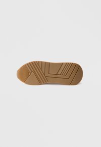 Suola di scarpa in gomma color marrone chiaro con motivi testurizzati, incluse linee diagonali e creste per la presa. Finitura liscia.