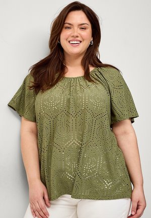Olive green blouse made of lightweight fabric with a rounded neckline and short sleeves. Features cut-out patterns in geometric shapes.