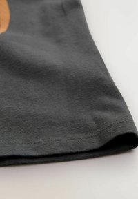 Tissu en coton gris avec une texture lisse, présentant un ourlet droit, des détails de couture subtils et un design décontracté et confortable.