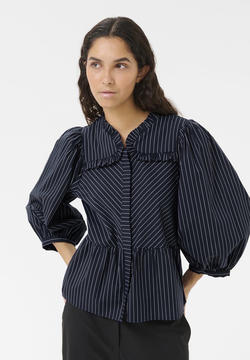 Marine gestreiftes Blusenshirt mit Rüschensaum, puffigen Ärmeln und einem Peplum-Taille. Der Stoff hat eine glatte Textur mit vertikalen weißen Streifen.