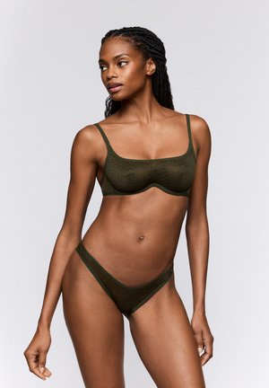 Lace bralette en bijpassende bikini in donkergroen. Zachte, doorschijnende stof met een bloemenpatroon. Lichtgewicht, verstelbare bandjes en minimalistisch ontwerp.