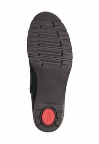 Suela de zapato negra con un patrón de relieve texturizado para el agarre, con un emblema circular rojo de "Comfort" cerca del talón y una superficie lisa.