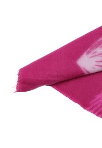 Tessuto rosa morbido e vibrante piegato con un bordo frangiato e un sottile motivo tie-dye bianco vicino a un angolo.