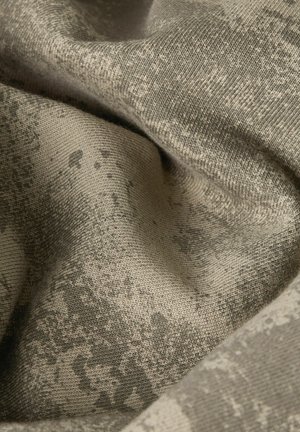 Close-up van beige textiel met een subtiel, iets donkerder onregelmatig patroon en een zacht, gebreid dessin.