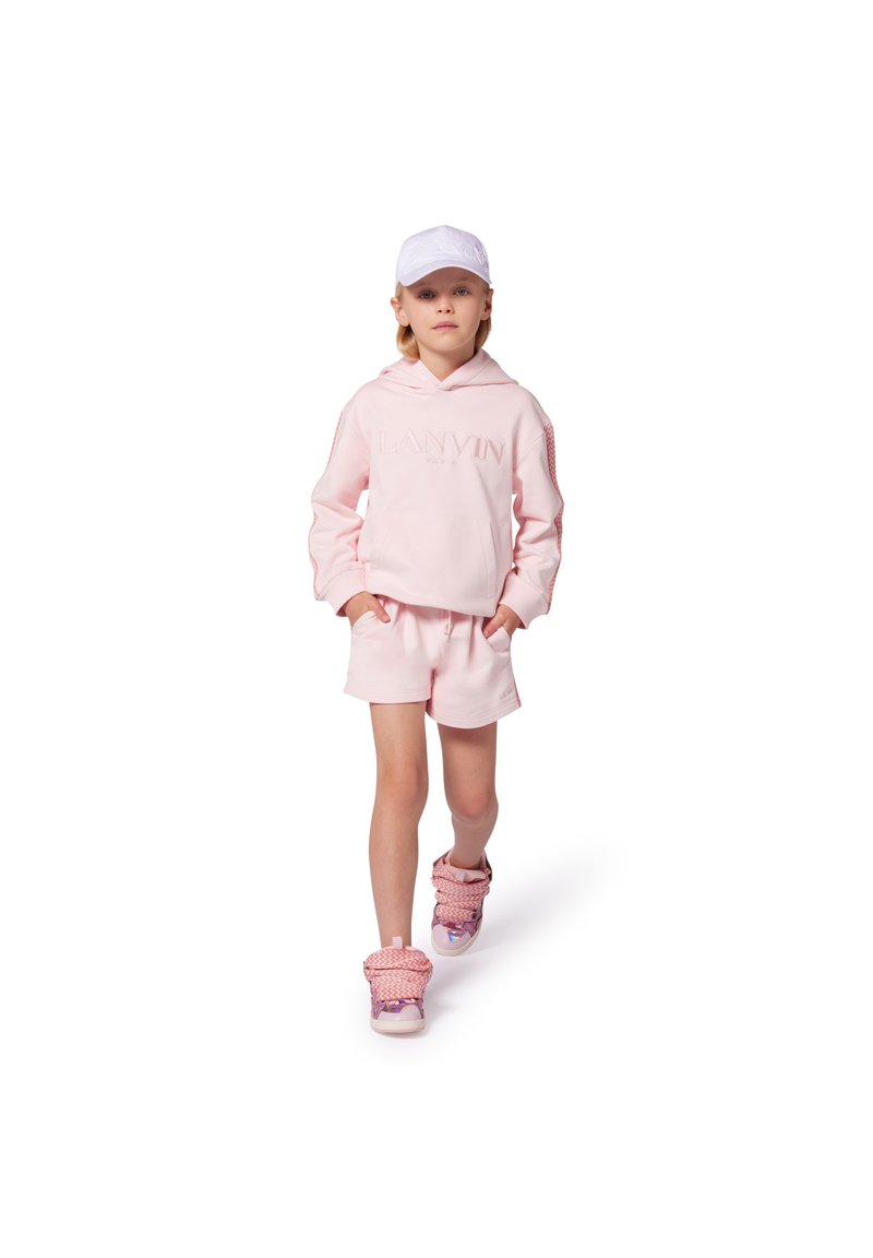 Felpa rosa chiaro con logo ricamato, pantaloni corti abbinati e sneakers rosa con motivo. Un cappellino bianco aggiunge un tocco casual. Tessuto liscio e morbido.