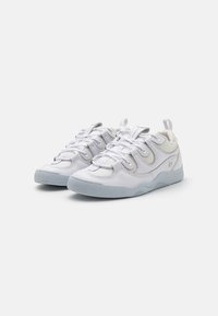 Weiße Sneaker mit einem strukturierten Lederobermaterial, Schnürverschluss und einer hellgrauen Gummisohle, die dezente Nähte und eine Schlaufe aufweist.