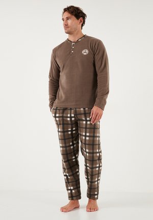 Haut long à manches en polaire marron avec patte de boutonnage et logo. Pantalons de pyjama à carreaux en marron, blanc et noir, avec une texture douce.