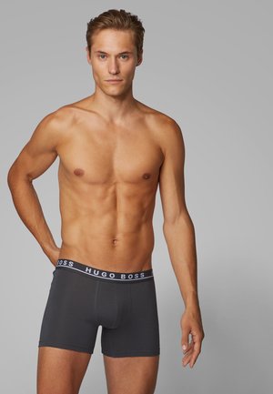 Männer Boxerbriefs aus dunkelgrauem Stoff mit einem kontrastierenden schwarzen Bund, der das Logo "HUGO BOSS" trägt. Weiche Textur und enganliegendes Design.