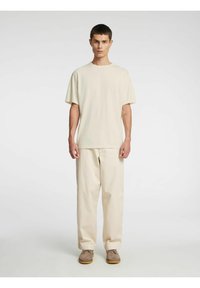 Helebeežikas kootud pehmetest puuvillast suurte mõõtmetega t-särk ja sobivad laiad püksid. Lihtne disain ilma nähtavate mustriteta, koosheledega kingadega.