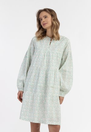 Rochie de culoare albastru deschis, cu un model floral, cu mâneci lungi și bufante și detalii plisate. Prezintă un decolteu mic în formă de cheie și un tiv în mai multe straturi.