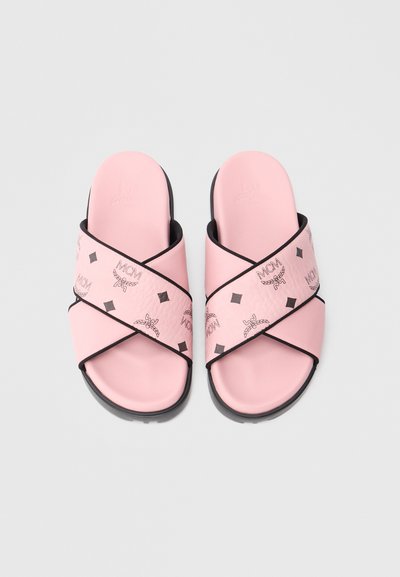 Pink slide-sandaler med et crossover-remdesign, der har et tekstureret bånd med sorte logoer og diamantmønstre, sorte såle accenter.