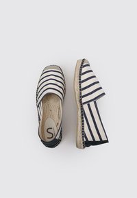 Espadrilles con un patrón a rayas en azul marino y crema, con una suela de yute trenzado y un tacón plano. Parte superior de tela suave y lados elásticos.
