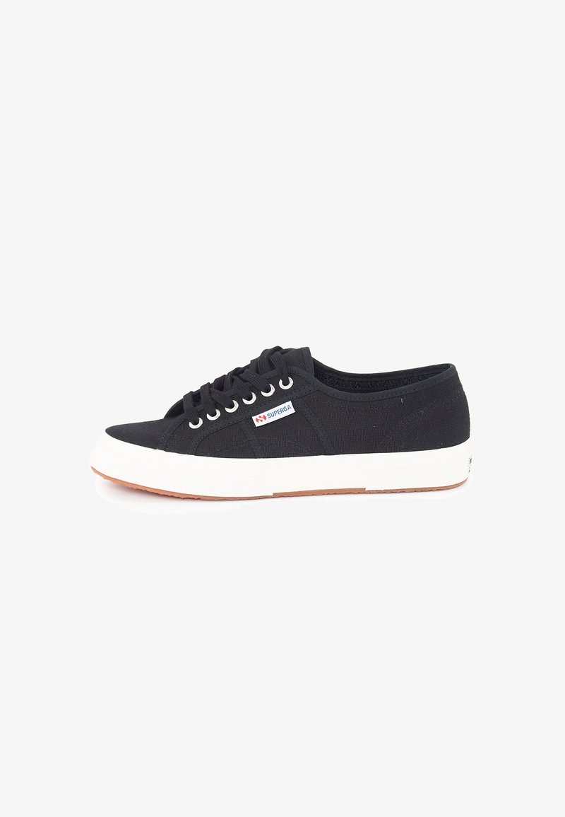 Mustat kanva sneakersit, joissa on valkoinen kumipohja, nauhakiinnitys ja pieni brändilogo lähellä nauhoja. Rakenteellinen pinta.