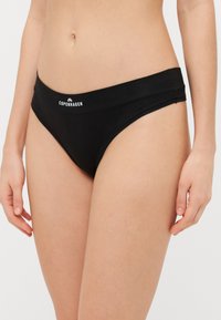 Black cotton bikini with a smooth texture and wide waistband, featuring the word "COPENHAGEN" in white lettering on the front.