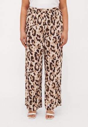 Wide-leg pants with beige and brown leopard print worn with white strappy sandals and a white top.