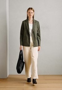 Riba roheline bleiser, valge särk, kreemjat värvi püksid, must kott ja plokknööpidega saapad. Sile tekstuur, mis on täpselt lõigatud ja sirge jala disain.