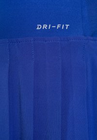 Tejido atlético azul con pliegues cosidos y logo de texto "DRI-FIT" en blanco impreso cerca de la parte superior central.