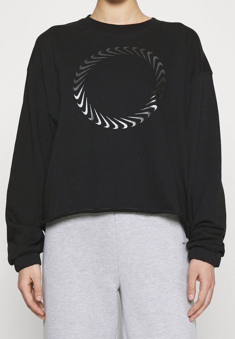 Svart kort sweatshirt med en rund silvrig grafisk design. Tyget ser mjukt ut med ribbade manschetter och en avslappnad passform.