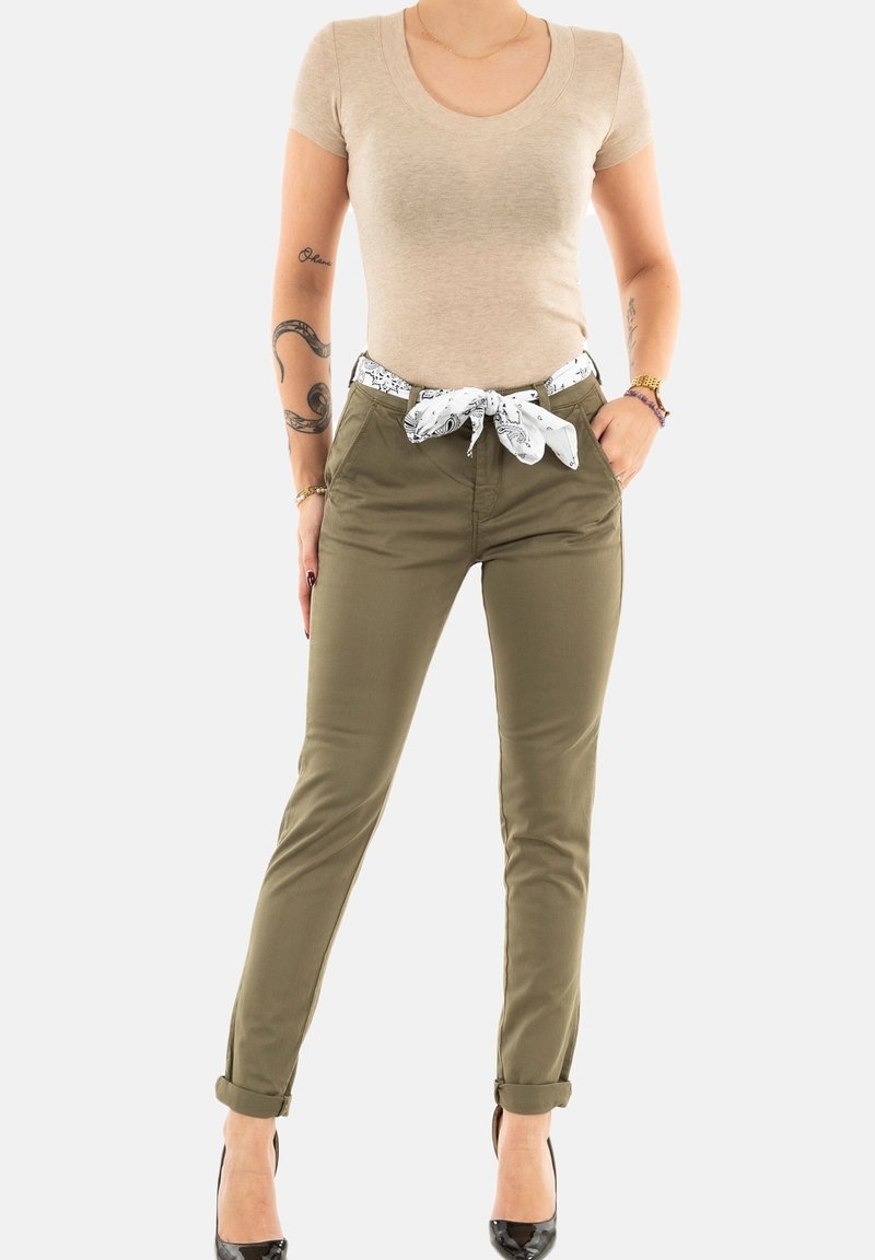 Beige korte mouwen top, olijfgroene broek met opgerolde manchetten,accentueert met een witte sjaal riem met patroon, en zwarte hoge hakken.