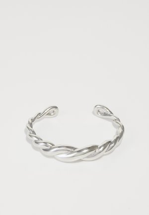 Silver cuff-armband med en vriden design, med en slät, glansig yta och öppna ändar. Enkel men distinkt kurvatur.