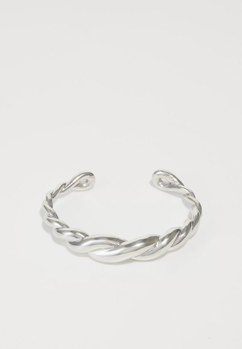 Hõbedane käevõru, millel on keeratud disain, sujuva ja läikiva pinnaga ning avatud otstega. Lihtne, kuid eristuv kõverus.