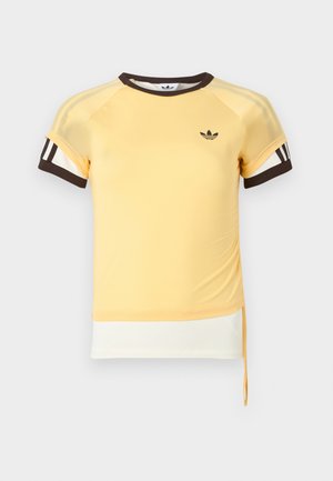 Κίτρινο αθλητικό μπλουζάκι με μανίκια raglan, καφέ λεπτομέρειες και τρεις λευκές ρίγες στα μανίκια. Διαθέτει λογότυπο και κορδόνι στο τελείωμα.