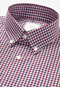 Chemise à carreaux rouge et marine, tissu coton, col boutonné, boutons blancs, étiquette portant la mention 'next tailored', légère texture due au motif tissé.