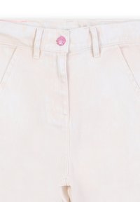 Beige denim jeans hebben een hoge taille, een subtiele geribbelde textuur en een roze knoop bij de taille. Klassiek ontwerp met vijf zakken is inbegrepen.