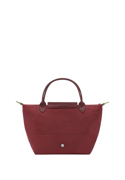 Rote Stofftragetasche mit braunen Ledergriffen und rechteckiger Form. Verfügt über eine Vordertasche und ein kleines Metall-Logo an der Unterseite.