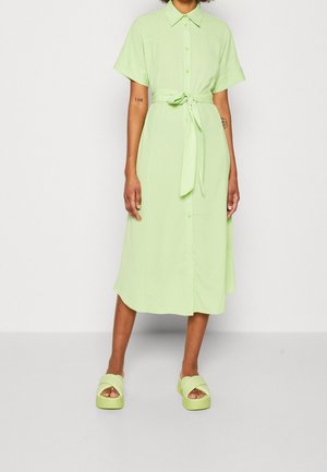 Světlounce zelené šaty s krátkými rukávy na zapínání na knoflíky, s páskem v pase, rovného střihu a měkké hladké textury. Doplněné o platformové sandály ve stejné barvě.