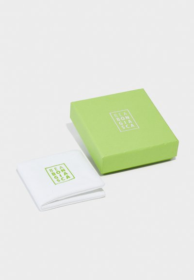 Λευκό βαμβακερό μαντήλι διπλωμένο δίπλα σε ένα πράσινο κουτί με άσπρο λογότυπο που αναγράφει "BEABONGIASC." Το κουτί έχει ματ και λείο υφή.