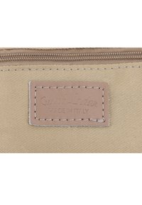 Béžová látková peněženka se zipovým uzávěrem a prošívanou hnědou koženou visačkou s embosovaným nápisem "Gusht.Leder MADE IN ITALY."