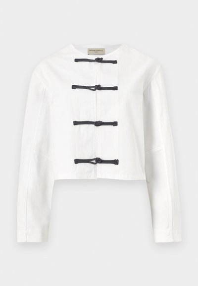 Λευκό cropped μπουφάν με μακριά μανίκια και τέσσερα μαύρα κουμπώματα με κόμπους μπροστά, στρογγυλή λαιμόκοψη, χωρίς γιακά.