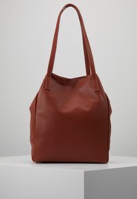 Bruine leren shopper met structuur, lange handvatten, zachte vorm en een licht slordige uitstraling. Compact en functioneel ontwerp.