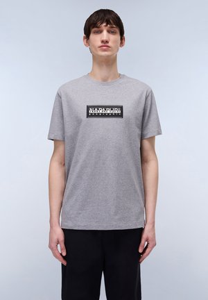 Grå kortærmet t-shirt med rund hals. Har et sort rektangulært logo på brystet, lavet af blødt, bomuldsagtigt stof.