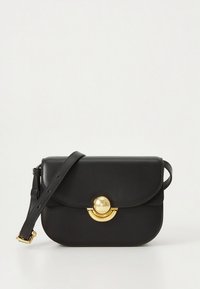 Black leather crossbody bag with a flap closure, gold circular hardware accent, and adjustable strap. Smooth texture and rounded shape.