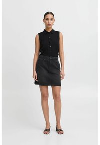 Blusa nera senza maniche con chiusura a bottoni, abbinata a una minigonna in denim nera con tasche anteriori e taglio dritto.