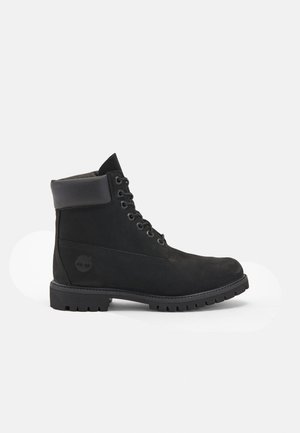 Black leather ankle boot with a rounded toe, six eyelet lace-up design, padded collar, textured sole, and Timberland logo on the side.