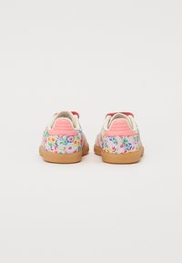 Floral sneakers with a multi-color fabric upper, pink heel accents, and a durable gum sole, showcasing a vibrant flower pattern.