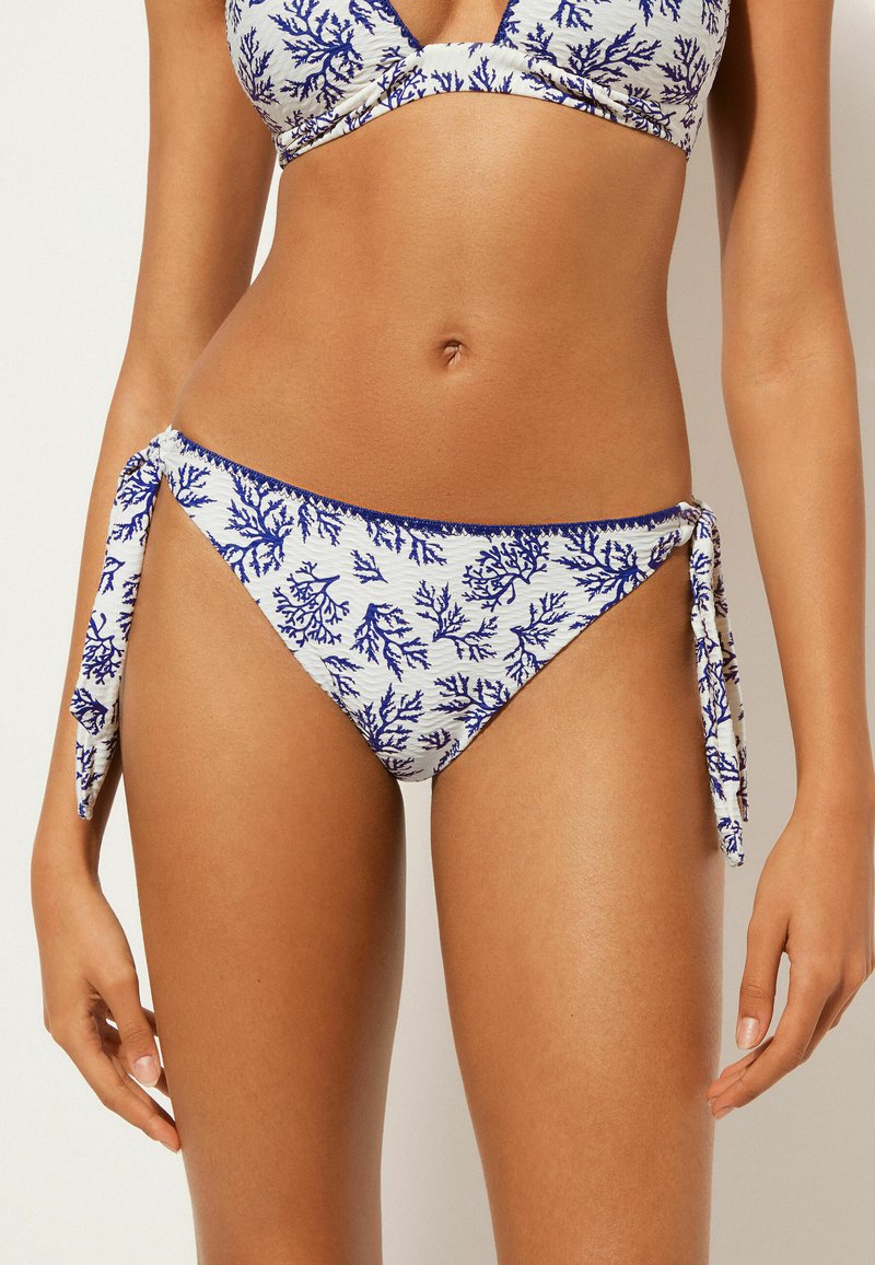 Bikini-set med ett mönster av koraller; toppen har en V-ringning. Botten har sidband, blå koralltryck på vit tyg med strukturerad yta.