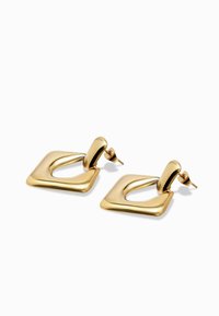 Zlatne metalne naušnice s kvadratnim dizajnom i zaobljenim rubovima te istaknutom petljom. Glatka tekstura s sjajnom završnom obradom. Kvadratni i suzeni oblici.