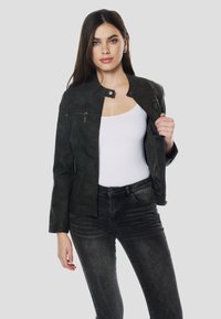 Čierna bunda z umelého koženého materiálu s krátkym strihom, predným zipsom a zapínaním na cvoky. Má jemný lesk a textúrované detaily na rukávoch.