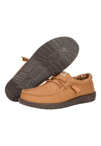 Zapatos casuales marrones con parte superior de lona, suela de goma marrón contrastante con patrones de agarre texturizados y un forro interior con estampado geométrico.