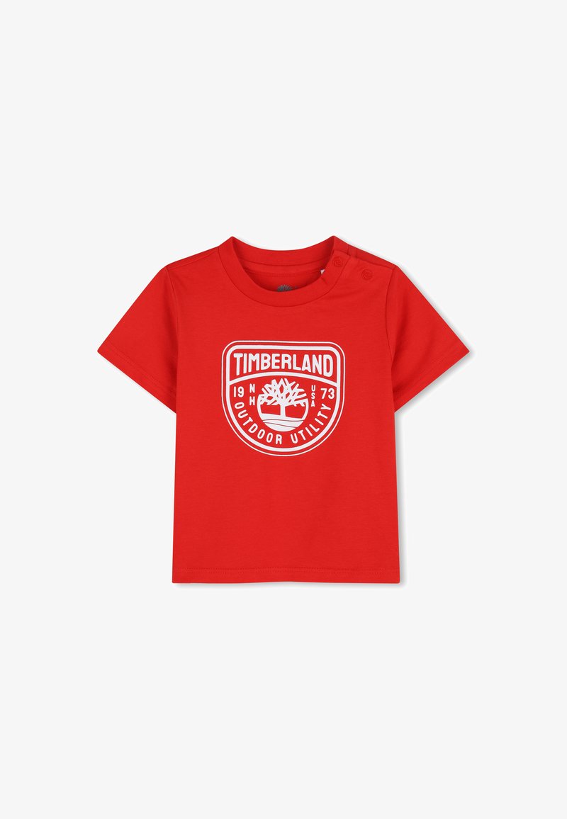 T-shirt rouge à manches courtes pour tout-petit avec logo Timberland blanc et pressions sur l'épaule gauche.