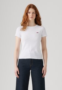 T-shirt en coton blanc à manches courtes et col rond, avec un petit logo rouge de Levi's sur la partie gauche de la poitrine. Coupe classique.