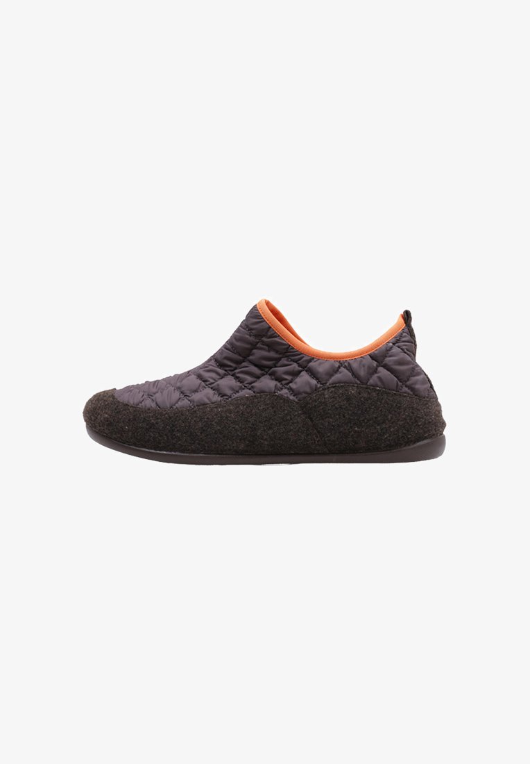 Zapato de tela acolchada negra tipo slip-on con acentos naranjas y una base de color marrón oscuro similar a la lana. Presenta una suela flexible y una forma redondeada.