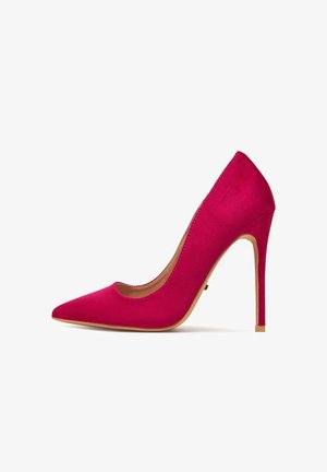 Roter Wildleder-Stiletto mit hohem Absatz, spitzer Zehenpartie und hellbrauner Sohle, im Profil vor weißem Hintergrund gezeigt.