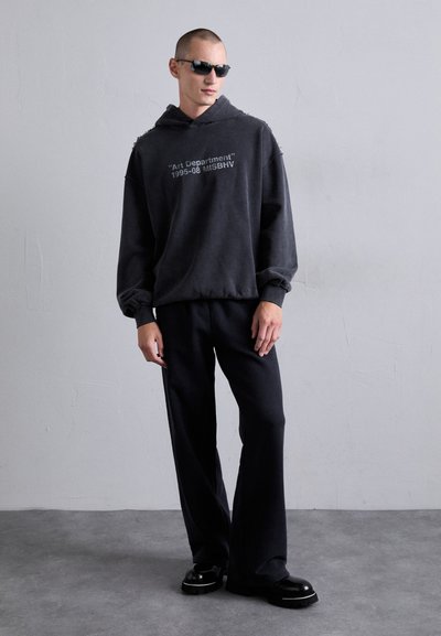 Mørkegrå hætte sweatshirt med tekstgrafik, parret med sorte brede bukser og chunky sorte sneakers. Glat stof og afslappet pasform.