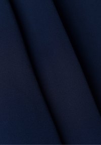 Tessuto blu navy con una superficie liscia e testurizzata, piegato per mostrare profondità e una leggera lucentezza. Il materiale appare leggero e flessibile.